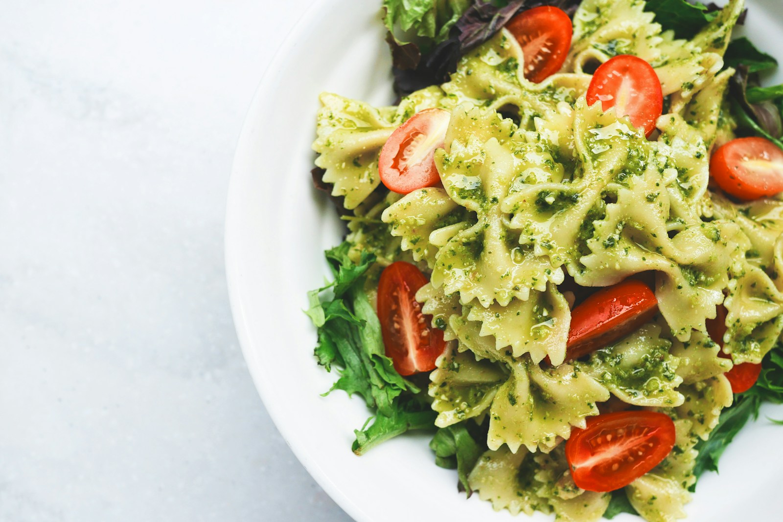 Pesto pasta with sliced tomatoes served on white ceramic plate The Moldy Food Trap