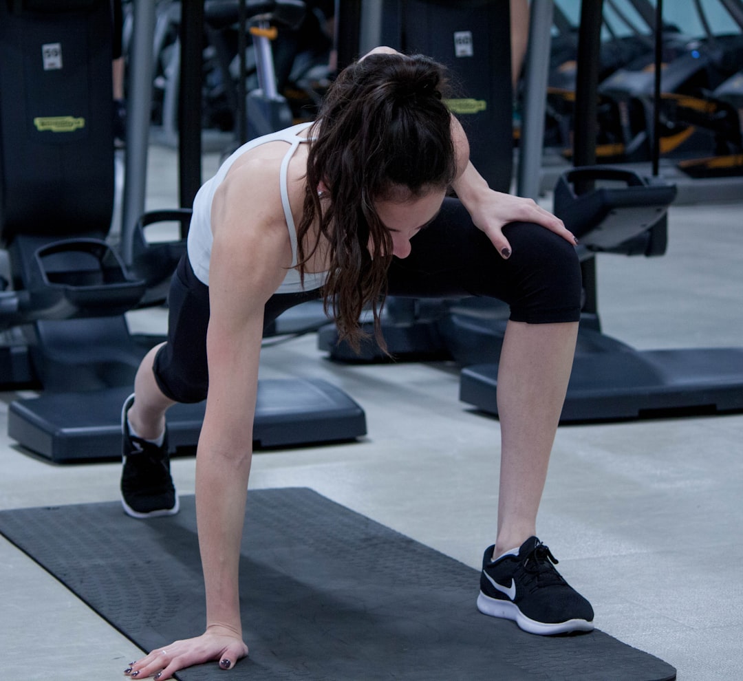 woman stretching legs and arms on black yoga mat - Exercise