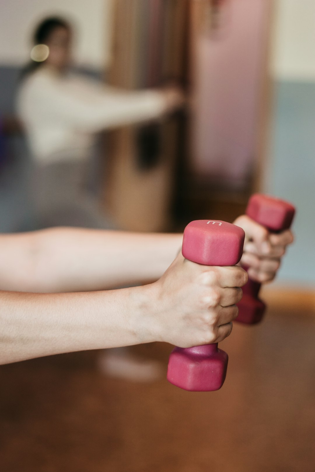 person holding pink and white dumbbells - Exercise