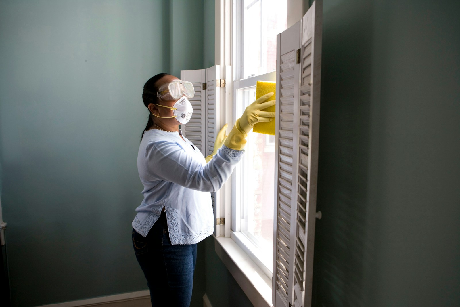 woman in white long sleeve shirt and blue denim jeans standing beside white wooden framed glass Mold at the Source