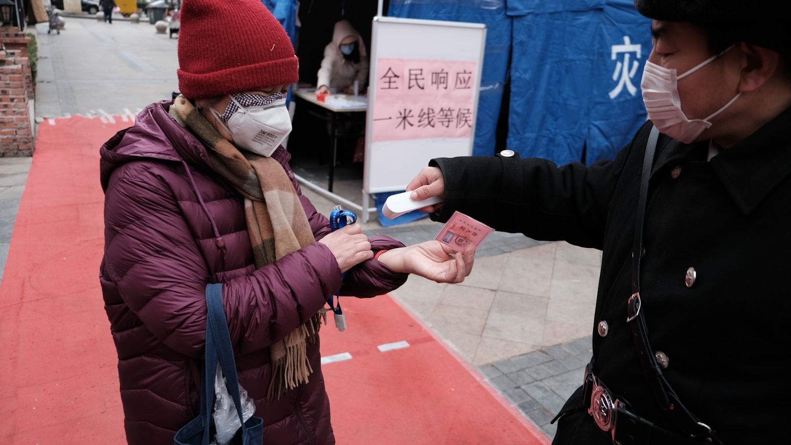 woman in red knit cap and red jacket holding white smartphone Vaccine-Induced Inflammation